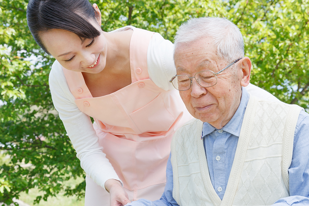 車椅子の利用者様に笑顔で寄り添う介護士